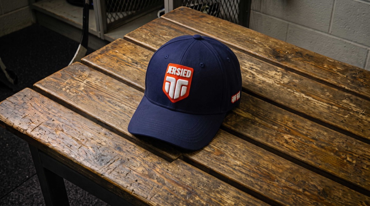 Navy Jersied cap with a red shield patch on a locker room bench